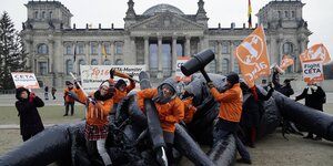 Menschen erlegen symbolisch vor dem Bundestag ein Plastikmonster.