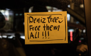 Gelbes Protestplakat an Autofenster mit der Aufschrift: Denz free, Smiley, free them All!!