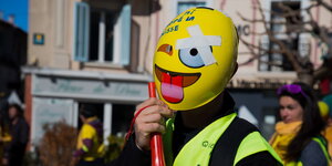 ein Mensch mit einer gelben Weste und einer gelben Maske mit einem Comic-Gesicht