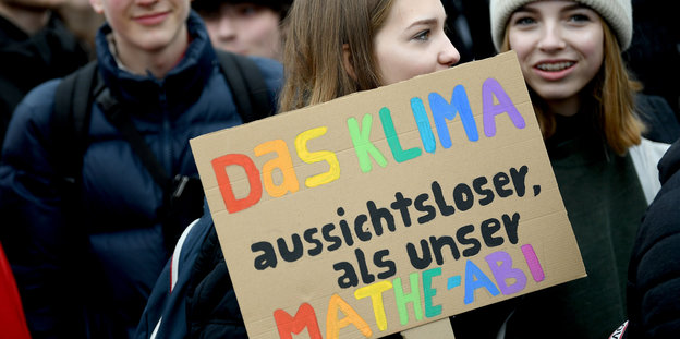 Ein Mädchen hält auf einer Demonstration ein Schild mit der Aufschrift: „Das Klima, aussichtloser als unser Mathe-Abi“