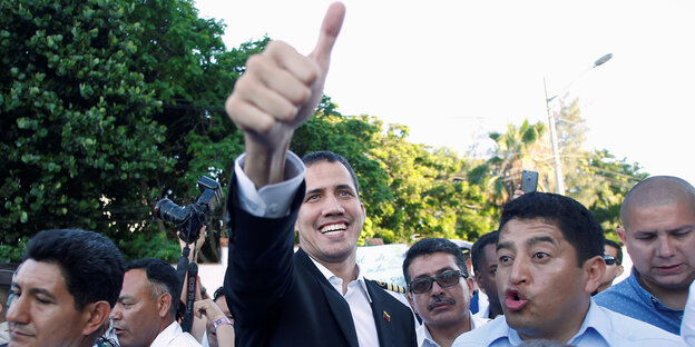 Juan Guaido reckt in einer Menschenmenge lächelnd den Daumen in die Luft