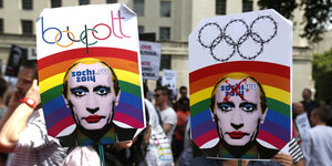 Menschen halten Plakate mit einem künstlerisch verfremdeten Gesicht Wladimir Putins in die Höhe