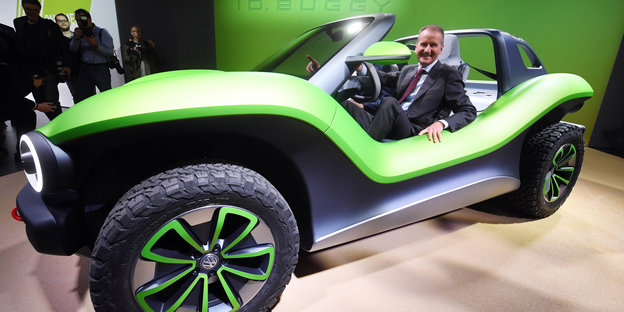 In einem offenen grünen Auto sitzt VW-Chef Herbert Diess