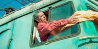 Ein Mann guckt aus dem Fenster eines knallig grünen Zuges