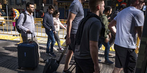 Menschen mit Rollkoffern gehen auf einem Fußgängerweg auf der Rambla in Barcelona
