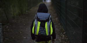 Schülerin mit leuchtendem Schulranzen auf dem Weg zur Schule