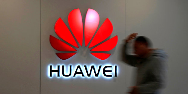 Ein Mann läuft an einem Huawei Logo vorbei