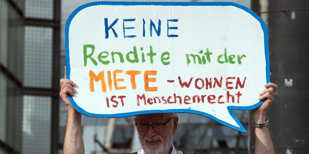 Ein Mann auf einer Demo mit einem Plakat in der Hand, auf dem steht: Keine Rendite mit der Miete