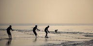 Fischer ziehen am Strand Netze ein