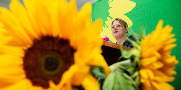 Im Vordergrund eine Sonnenblume, im Hintergrund Maike Schäfer (Grüne)