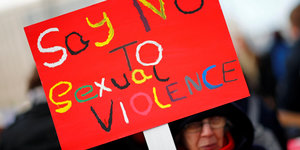 Eine Frau hält ein Schild mit einem Slogan gegen sexualisierte Gewalt hoch