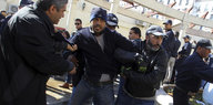Polizisten in Zivil halten einen Demonstranten fest