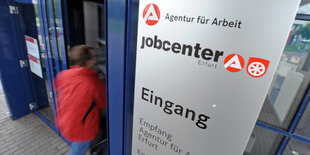 Ein Mensch geht durch den Eingang eines Jobcenters