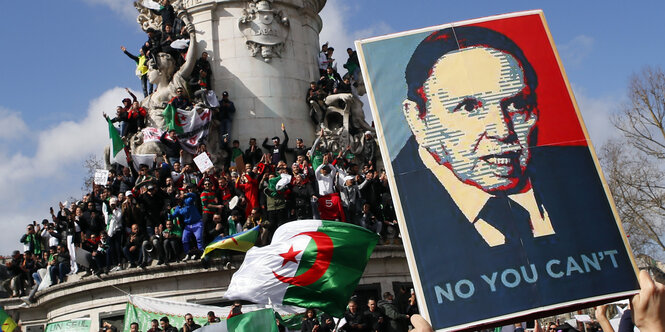 Demonstranten halten ein Plakat hoch, auf ihm ist das Porträt eines alten Mannes abgebildet. "No, you can't" steht darunter