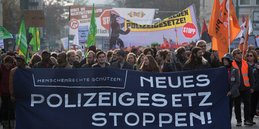 Demonstration gegen das Polizeigesetz: Demonstrantinnen und Demonstranten halten Banner und Fahnen und marschieren auf der Straße