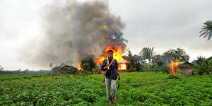 Ein Rakhine steht in Sittwe vor einem brennenden Haus