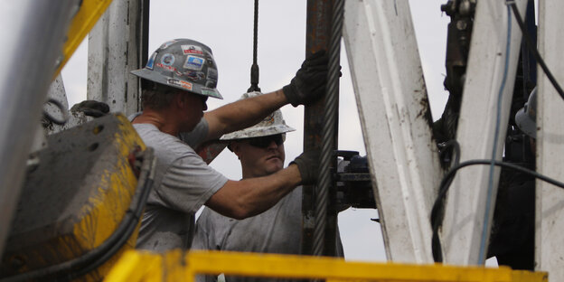 Arbeiter mit Helmen auf einem Bohrturm