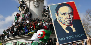 Hunderte Demonstranten klettern auf ein Gebäude, viele tragen algerische Fahnen, ein Schild mit dem Konterfei von Abdelaziz Bouteflika und der Aufschrif "No you can't" wird nach oben gehalten