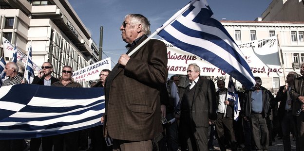 Demonstranten halten Griechenland-Fahnen und Transparente nach oben