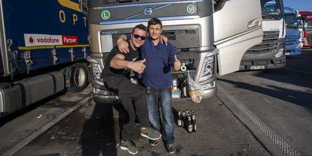 Zwei Männer und viele Bierflaschen vor einem Lkw