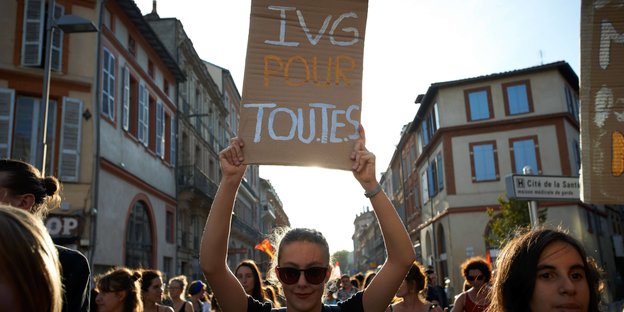 Eine junge Frau hält ein Plakat hoch, auf dem auf Französisch "Schwangerschaftsabbrüche für alle" steht
