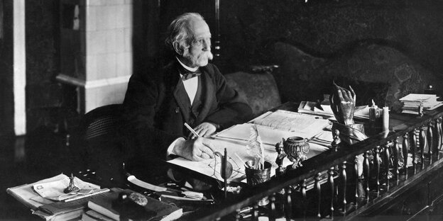 Theodor Fontane ist auf einer Schwarz-Weiß-Fotografie an seinem Schreibtisch zu sehen
