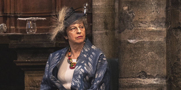 Theresa May sitzt gedankenverloren in einer Kirche