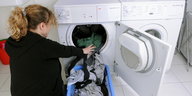 eine Frau kniet vor einem Wäschetrockner
