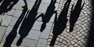 Eine Familie wirft lange Schatten auf Kopfsteinpflaster