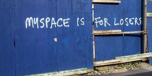 Blaue Wand mit dem Graffito "Myspace is for Loosers"