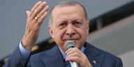 Erdoğan spricht mit erhobener Hand in ein Mikrofon.
