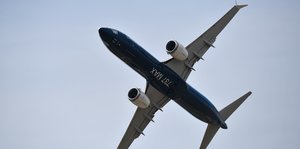 Ein Flugzeug fliegt vor weiß-blauem Himmel, auf dem Bauch stehen die Zahlen 737 und die Buchstaben M A X