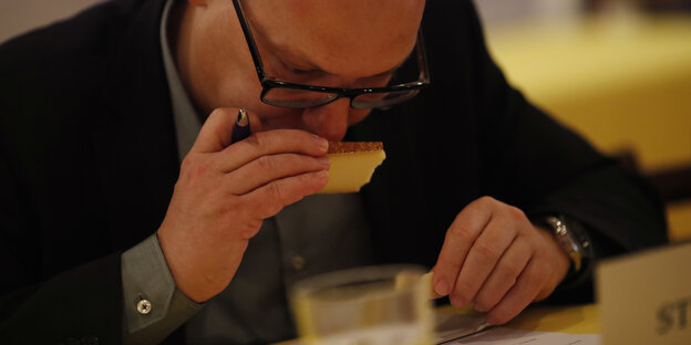 Ein Mann riecht an einem Stück Käse