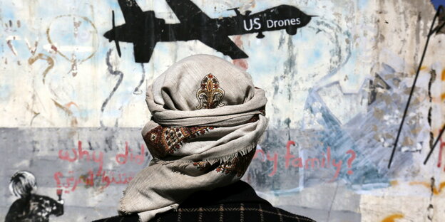 Ein Jemenit steht vor einem Graffiti, mit dem gegen US-Drohnenoperationen protestiert wird.