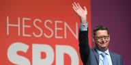 Ein Mann winkt vor einem Schild mit der Aufschrift Hessen SPD