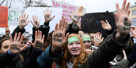 Jugendlich auf einer Klimademo, sie strecken die Innenhand nach vorn, auf ihnen steht: "Our Future" und "In your hands"