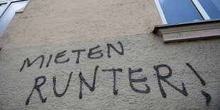 "Mieten runter!" steht als Graffito an einer grauen Hauswand