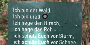 Ein Schild mit Aufschrift, an einem Baum befestigt