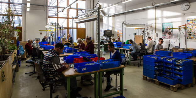 Menschen arbeiten in einer Werkstatt der Berliner Werkstätten für Menschen mit Behinderung