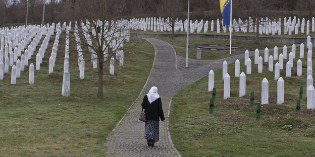 Eine Frau zwischen Kreuzen in der Gedenkstätte für die Opfer von Srebrenica