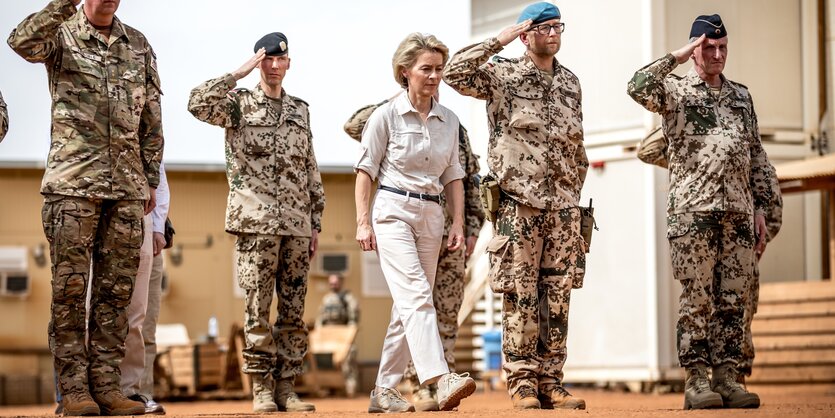 Ursula von der Leyen steht zwischen salutierenden uniformierten Soldaten