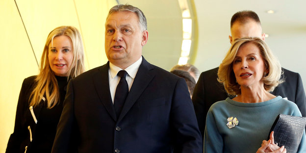 Viktor Orban, ein Mann in Anzug und Krawatte, rechts und links von ihm sind Frauen zu sehen