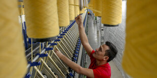 An einer Fachmaschine arbeitet der Lehrling im ersten Lehrjahr zum Maschinen- und Anlagenführer für Textiltechnik Salman Mirzaei aus Afghanistan in der Zwickauer Kammgarn GmbH in Wilkau-Haßlau