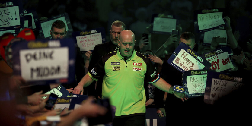 Ein Mann, Michael van Gerwen, mit Fans, die Schilder hochhalten