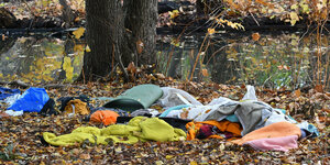 Schlafsäcke, Isomatte und Klammoten liegen zwischen Laub in einem Waldstück