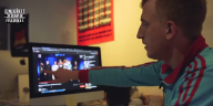 Der Journalist Hubertus Koch zeigt auf einen Laptop, auf dem ein Ausschnitt eines Rapbattlevideos zu sehen ist