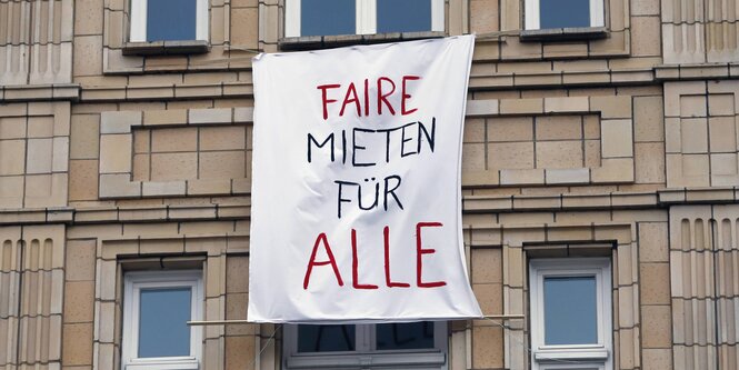 Auf einem Transparent, das aus einem Fenster hängt, steht "Faire Mieten für alle"