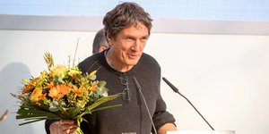 Autor Harald Jähner mit Blumen in der Hand auf der Bühne