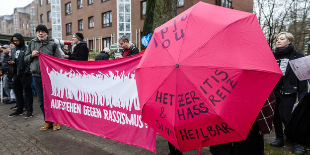 Eein Frau hält einen Regenschirm mit der Aufschrift "Hetzeritis & Hassreiz sind heilbar"