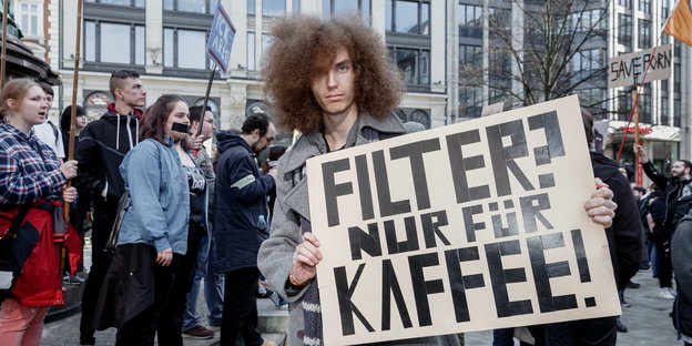 ein Mann hält ein Schild hoch, auf dem steht „Filter? Nur für Kaffee!“